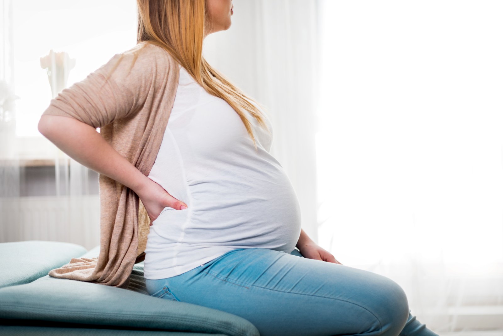 Pregnant woman holding her lower back due to pregnancy back pain