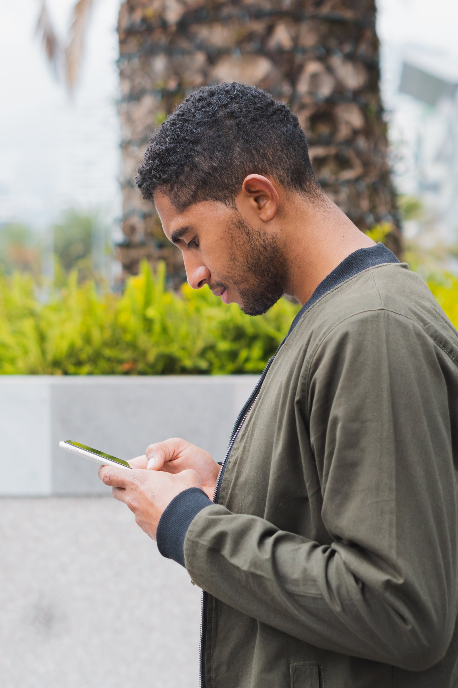 Person bending their neck looking down at a smartphone, causing tech neck