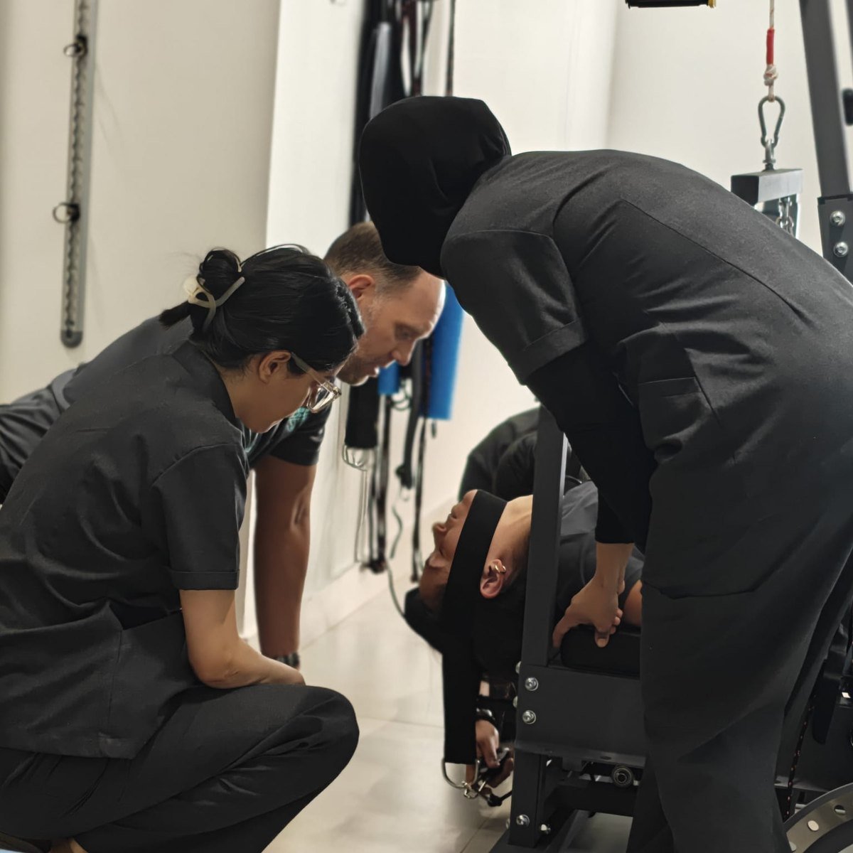 Clinical team guiding a patient on the spinal correction device at CBP Precision Spine Center, Muscat