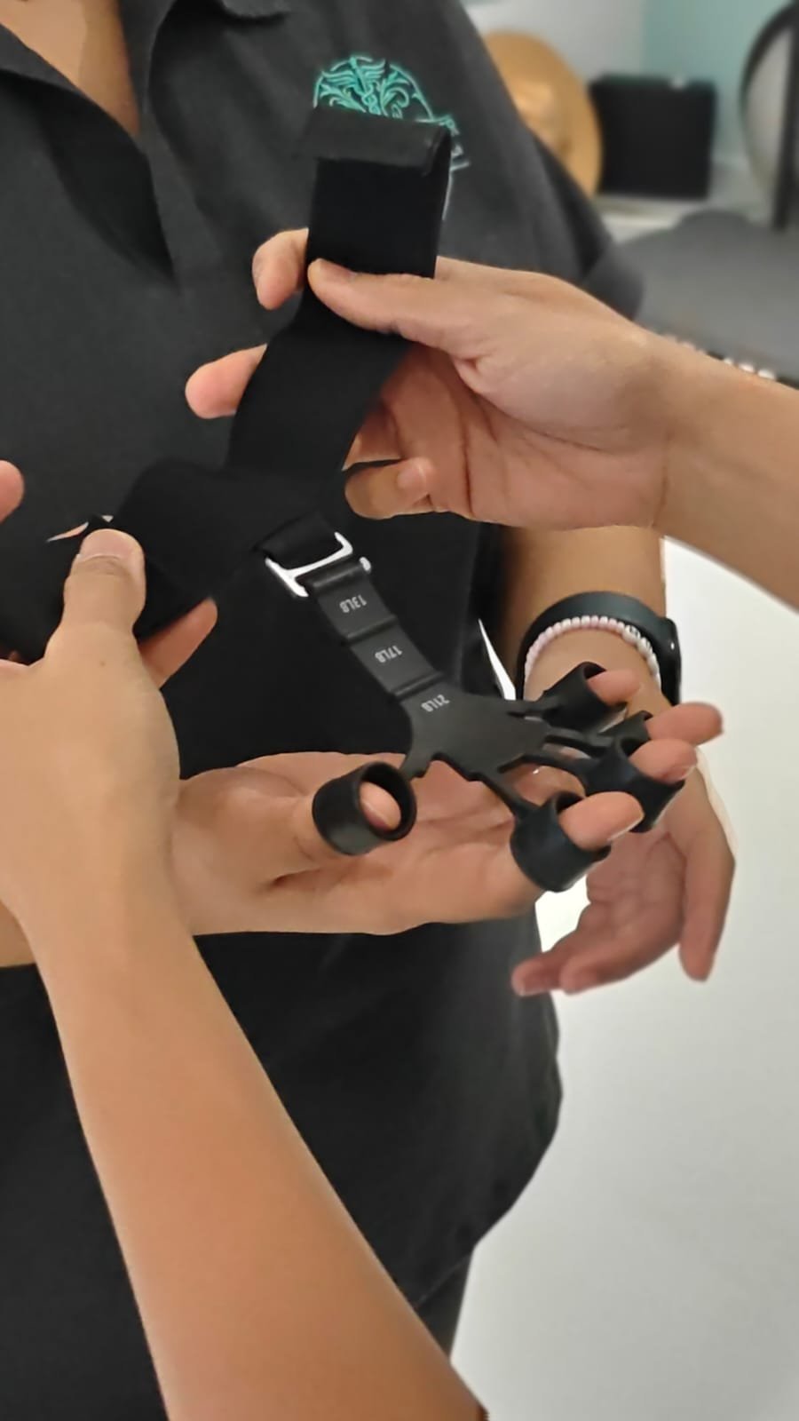 Therapist fitting a finger and grip resistance exerciser on a patient hand at CBP Precision Spine Center