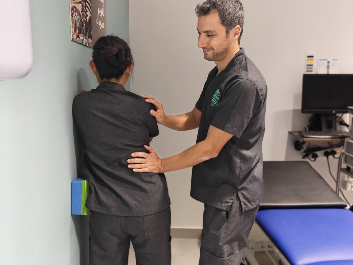 Physiotherapist assessing a patient's standing posture against the wall, Muscat