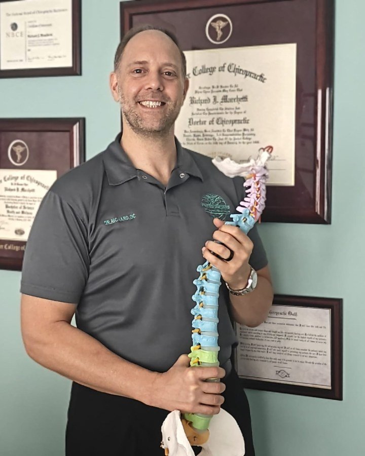Dr. Richard Marchetti, DC, holding an anatomical spine model