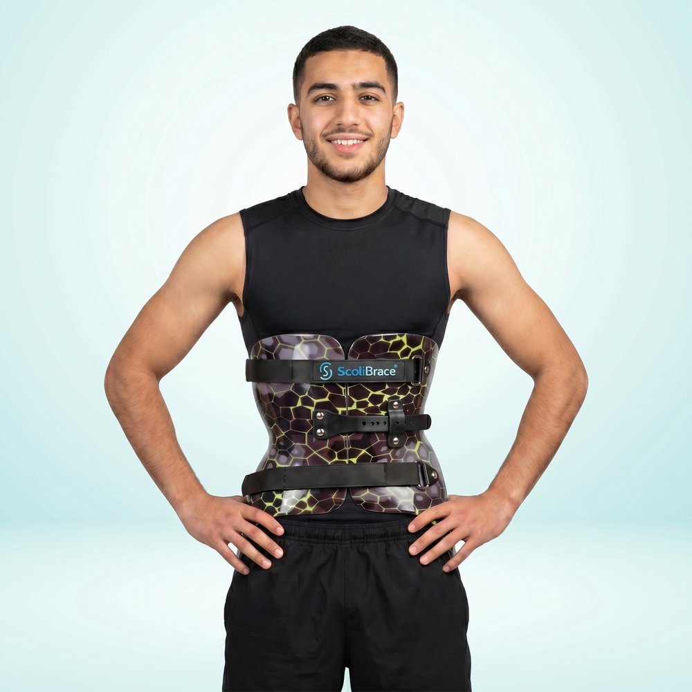 Young male patient fitted with a custom-printed ScoliBrace spinal brace, hands on hips