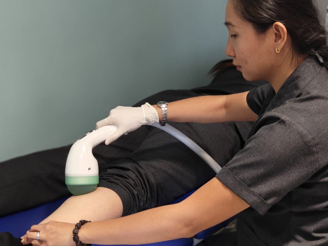 Therapist applying shockwave therapy to a knee